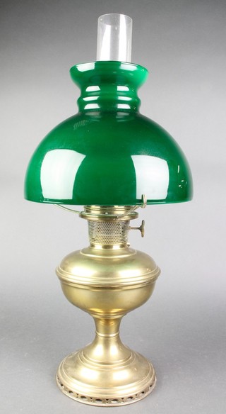 A brass oil lamp with clear glass chimney and green glass shade 