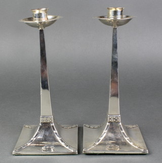 A pair of silver Arts & Crafts tapered candlesticks with circular sconces and spread base with faux rivet decoration 8 1/4" 