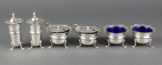 A 6 piece silver condiment set with cut edges and hoof feet comprising 2 peppers, 2 table salts with blue glass liners and 2 hinged mustard pots with blue glass liners and spoons, Birmingham 1916, 216 grams