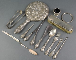 A silver backed circular hand mirror with floral decoration Birmingham 1928, a pair of Georgian silver sugar nips, a Victorian cast silver fork and spoon, a part mounted manicure set and minor items 