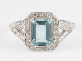 An 18ct white gold aquamarine and diamond dress ring, the baguette cut aquamarine surrounded by 35 brilliant cut diamonds, size M 