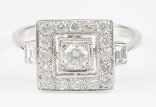 An 18ct white gold Art Deco style square shaped diamond ring, the centre brilliant stone surrounded by 16 brilliants and 2 baguettes size O, approx 0.75ct 