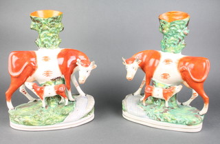 A pair of 19th Century Staffordshire vases in the form of standing brown and white cows with calfs 11" 