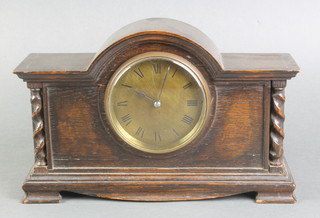 A 1930's bedroom timepiece with brass dial and Roman numerals contained in an arch shaped oak case 