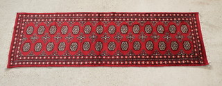 A Royal Mori Bokhara style red ground runner with 14 octagons to the centre 99" x 32" 