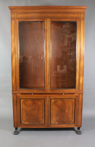 A Regency style mahogany display cabinet enclosed by glazed panelled doors, the base fitted a brushing slide above a cupboard enclosed by panelled doors with ebonised stringing throughout and raised on paw feet 90"h x 52 1/2"w x 17 1/2"d 