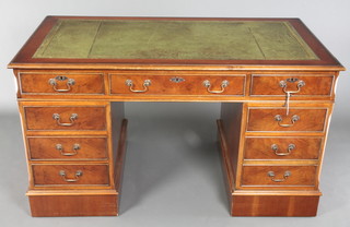 A yew pedestal desk with inset green leather writing surface above 1 long and 8 short drawers, raised on a platform base 30"h x 54"w x 29 1/2"d 