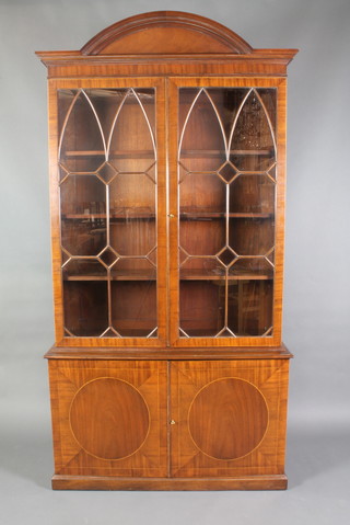 A Georgian style mahogany library bookcase, the upper section with arched cornice and adjustable shelves enclosed by astragal glazed doors, the base fitted a double cupboard enclosed by inlaid panelled doors and raised on a platform base 93"h x 48"w x 16"d 