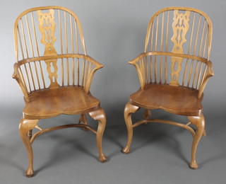 A pair of elm Windsor stick back carver chairs with solid seats, raised on cabriole supports with crinoline stretcher 