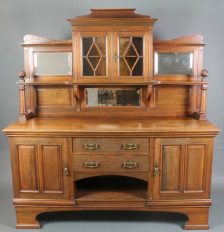 James Shoolbred Co., An Edwardian Art Nouveau walnut chiffoniere sideboard, the raised mirrored back fitted a cupboard enclosed by astragal glazed doors above 2 long drawers with recess flanked by a pair of cupboards, raised on shaped bracket feet 78"h x 72"w x 24"d 