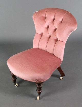 A Victorian nursing chair upholstered in rose pink buttoned draylon, raised on fluted supports 