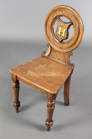 A Victorian oak hall chair with shield shaped back and solid seat, raised on turned supports