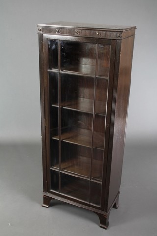 An Edwardian Art Nouveau ebonised display cabinet, fitted shelves enclosed by astragal glazed panelled doors, raised on a platform base 54"h x 21"w x 12"d 