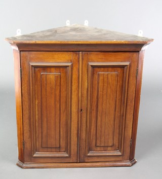 A Victorian walnut hanging corner cabinet with moulded cornice and shelved interior enclosed by panelled doors 24"h x 24 1/2"w x 13 1/2"d 