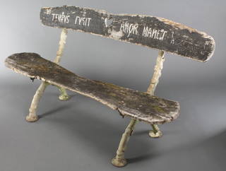 An antique rustic cast iron garden bench, the frame in the form of tree roots, with wooden plank seat and back, the back painted Latin inscription "Time flies, Love endures" 