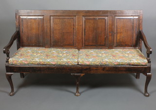An 18th Century oak settle of panelled construction and solid seat, raised on cabriole supports 41 1/2"h x 73"w x 25"d 