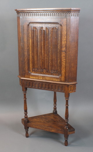 A Victorian carved oak corner cabinet with arcaded decoration fitted a shelf and enclosed by a linen fold panelled door raised on turned and block supports with under tier 60"h x 28"w x 17"d 