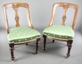 A pair of Victorian carved oak slat back dining chairs with upholstered seats, raised on turned supports 