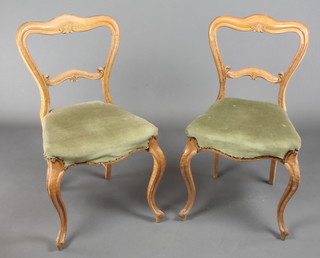 A pair of Victorian birdseye maple buckle back chairs with shaped mid rails and seats of serpentine outline, raised on cabriole supports 