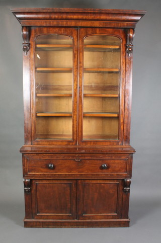 A Victorian mahogany secretaire bookcase, the upper section with moulded cornice enclosed by a pair of panelled doors and with vitruvian scrolls to the side, the base fitted a secretaire drawer above a double cupboard, raised on a platform base 93 1/2"h x 54"w x 17"d 