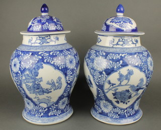 A pair of 20th Century Chinese blue and white urns and covers with panels decorated birds amidst flowering branches, the base with seal mark 17" 