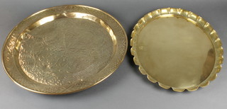 An oval brass tray with scalloped edge 20 1/2" x 16" together with a circular embossed brass charger 22" 