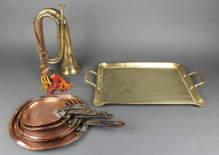 A brass bugle, a rectangular planished brass twin handled tea tray 14", 5 graduated circular copper saucepan lids with iron handles 9 1/2", 8", 7", 6" and 5 1/2" 