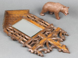 A wooden carved Swiss model of a walking bear 5" (foot f) and a rectangular bevelled plate mirror contained in a carved and pierced wooden frame 13" x 7"