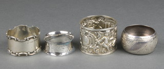 A Victorian silver napkin ring, the repousse decoration with cherubs amongst ruins, 3 others 