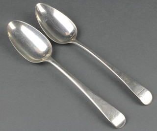 A near pair of George III silver table spoons with chased armorial and monogram 124 grams