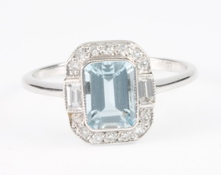 An 18ct white gold aquamarine and diamond ring, the centre emerald cut stone surrounded by 14 brilliant cut and 2 baguette cut diamonds, size L 1/2