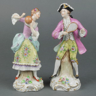 A pair of early 20th Century Sitzendorf figures of a gentleman playing tennis and a lady playing with a ball, on raised rococo bases 6 1/4" 