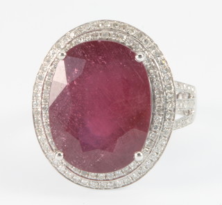 A 14ct white gold ruby and diamond dress ring, the centre oval cut stone approx. 13.5ct surrounded by brilliant cut diamonds approx 1.25ct 