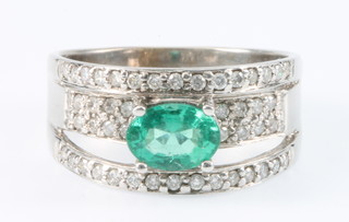 An 18ct white gold emerald and diamond dress ring with a centre cut emerald surrounded by 46 brilliant cut diamonds, size N