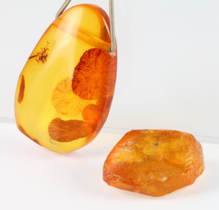 A pear shaped amber pendant and an unpolished amber bead