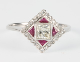An 18ct white gold Art Deco style ruby and diamond ring with 24 brilliant cut diamonds surrounding 1 brilliant cut diamond and 4 triangular cut rubies, size N