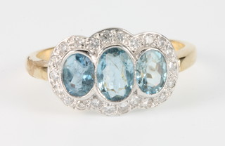 An 18ct white gold 3 stone aquamarine and diamond cluster ring, the 3 oval cut stones surrounded by 22 brilliant cut diamonds, size N 1/2