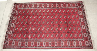 A Turkmen red ground carpet with 75 octagons to the centre 42" x 92", some wear