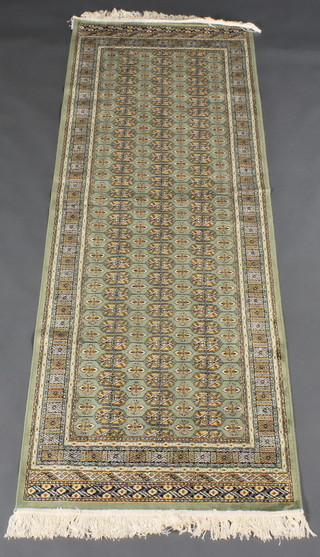 A green ground Belgian cotton Bokhara style runner with numerous octagons to the centre 82" x 28"