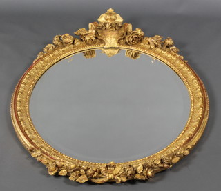 An oval bevelled plate wall mirror contained in a decorative gilt frame surmounted by a shield and rose garland 42"h x 34"w
