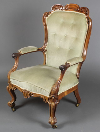 A Victorian carved mahogany show frame arm chair, upholstered in green buttoned Dralon, raised on cabriole supports