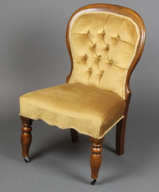 A Victorian mahogany show frame nursing chair upholstered in yellow buttoned Dralon, raised on turned supports (cut down) 