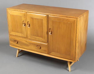 An Ercol light elm sideboard, fitted a cupboard enclosed by a pair of panelled doors above 1 long drawer and flanked by a cupboard enclosed by a panelled door, raised on turned supports 32"h x 45"w x 17"d 