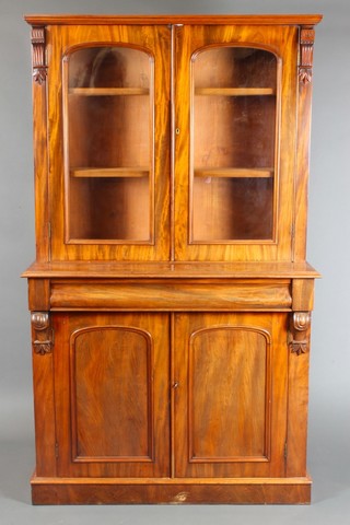 A Victorian mahogany cabinet on cabinet, the upper section with arched panelled doors and Vitruvian scrolls to the side, the base fitted a secret drawer above cupboard enclosed by arched panelled doors 72"h x 42"w x 18 1/2"d 