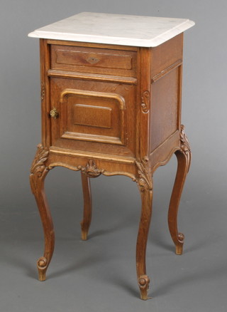 A 19th Century French carved oak bedside cabinet with white veined marble top fitted a drawer above a cupboard enclosed by panelled door, raised on cabriole supports 34"h x 17"w  x 17"d