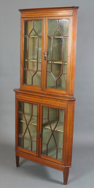 An Edwardian inlaid mahogany double corner cabinet, the upper section with moulded cornice, fitted a cupboard enclosed by astragal glazed doors, the base fitted a cupboard enclosed by astragal glazed doors with satinwood stringing, raised on square tapered supports 76"h x 33"w x 23"d 