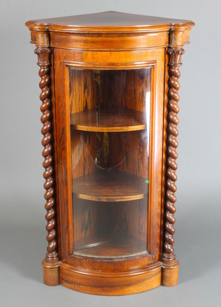 A Victorian rosewood bow front corner cabinet with spiral turned columns and acanthus style capitals, fitted shelves enclosed by a panelled door 43"h x 25 1/2"w x 20"d 