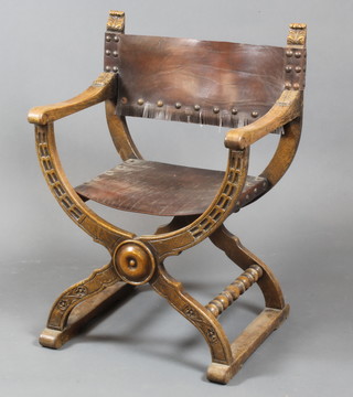 A Roman style carved oak show frame, X framed open arm elbow chair with leather seat and back 