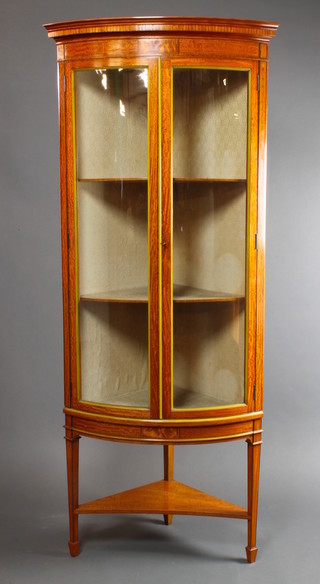 A Sheraton revival Edwardian inlaid satinwood corner cabinet with moulded and dentil cornice, having swags to the sides, fitted shelves enclosed by glazed panelled doors with triangular under tier, raised on square tapering supports ending in spade feet 72"h x 29 1/2"w x 20"d  