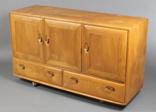 A 1960's Ercol light elm sideboard fitted 3 cupboards enclosed by panelled doors, the base fitted 2 long drawers, raised on casters 30"h x 51"w x 17"d 